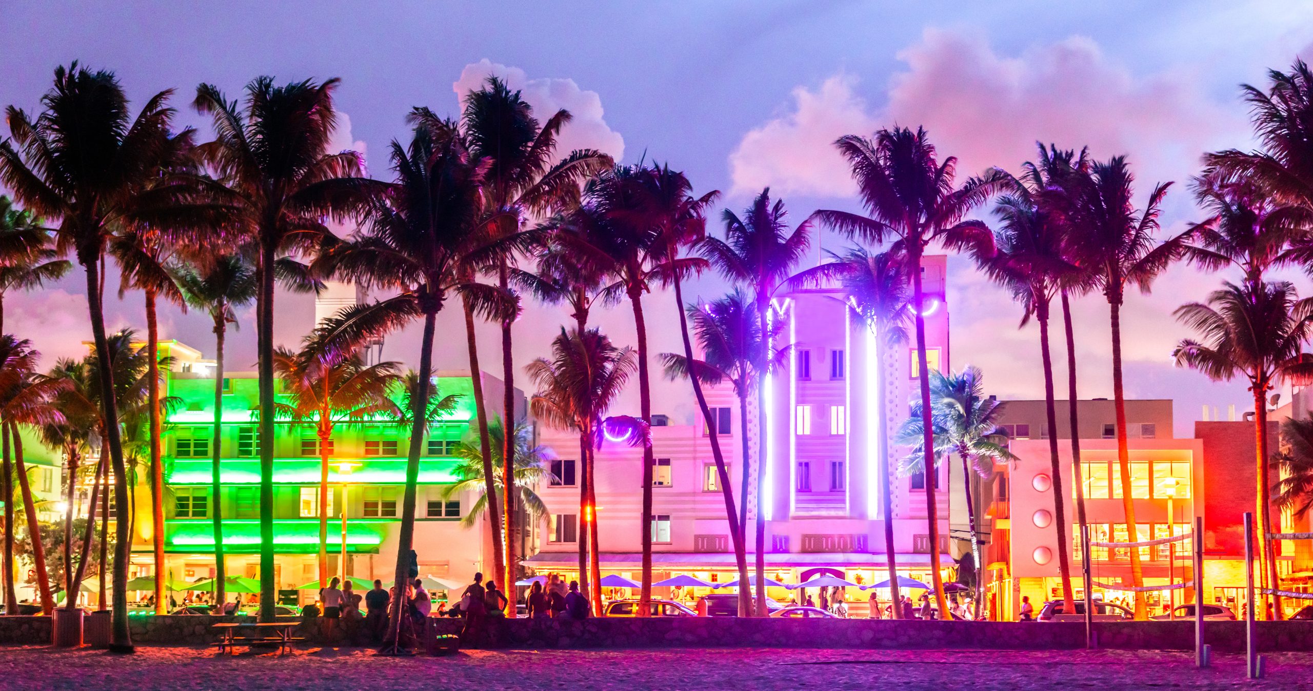 Miami Beach Ocean Drive hotels and restaurants at sunset. City skyline with palm trees at night. Art deco nightlife on the South beach